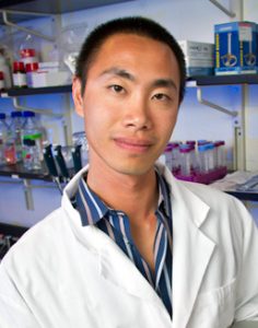 Desmond Lun in lab holding laptop